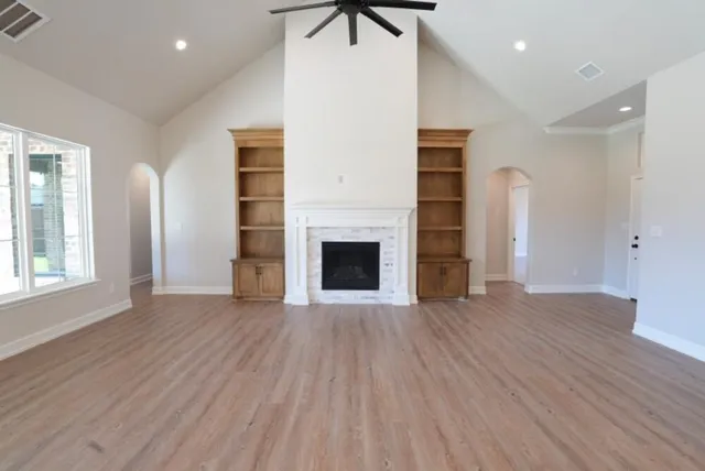 an empty room with wooden floor a fireplace and windows