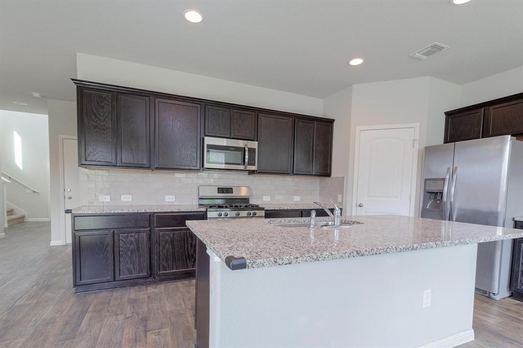 14614 Frankel Loop Pflugerville, TX 78660 - Photo 4 of 15 A well-appointed kitchen features dark wood cabinetry, granite countertops, and modern stainless steel appliances.