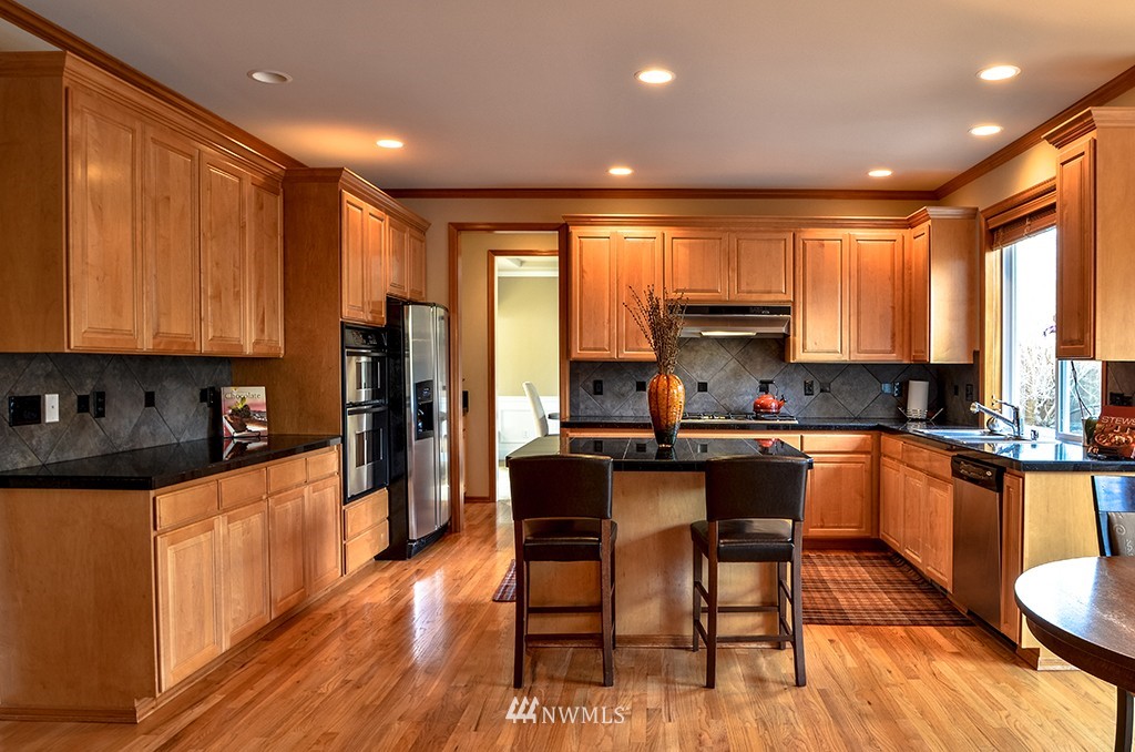 3723 207th Place Southeast Bothell, WA 98021 - Photo 5 of 15 a kitchen with stainless steel appliances granite countertop a stove top oven a sink dishwasher a dining table and chairs with wooden floor