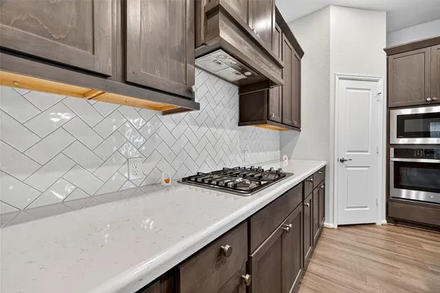 a large kitchen with stainless steel appliances a large counter top a stove and a refrigerator