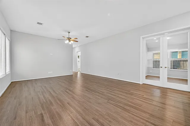 a view of an empty room with wooden floor and a window