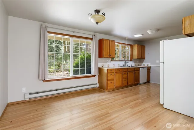 a view of kitchen with stainless steel appliances granite countertop a stove top oven a sink with wooden floors and floors
