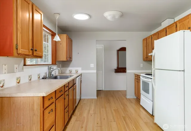 a kitchen with a sink a refrigerator a stove top oven and wooden floor