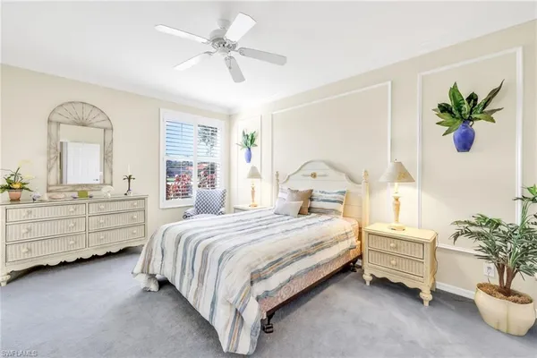 a bedroom with a bed potted plant on dresser and a window