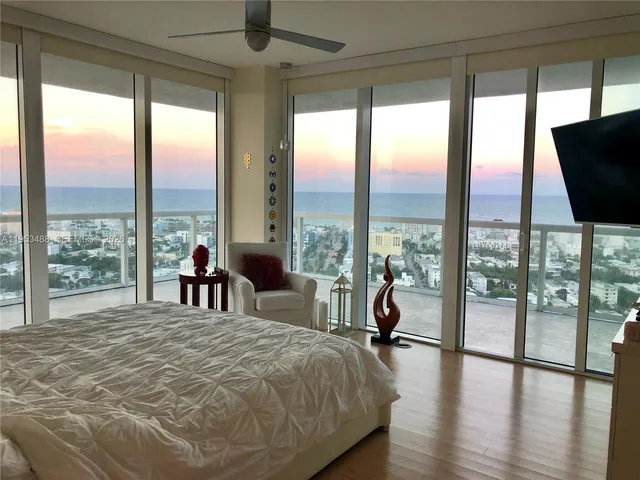 a spacious bedroom with a large window and a balcony