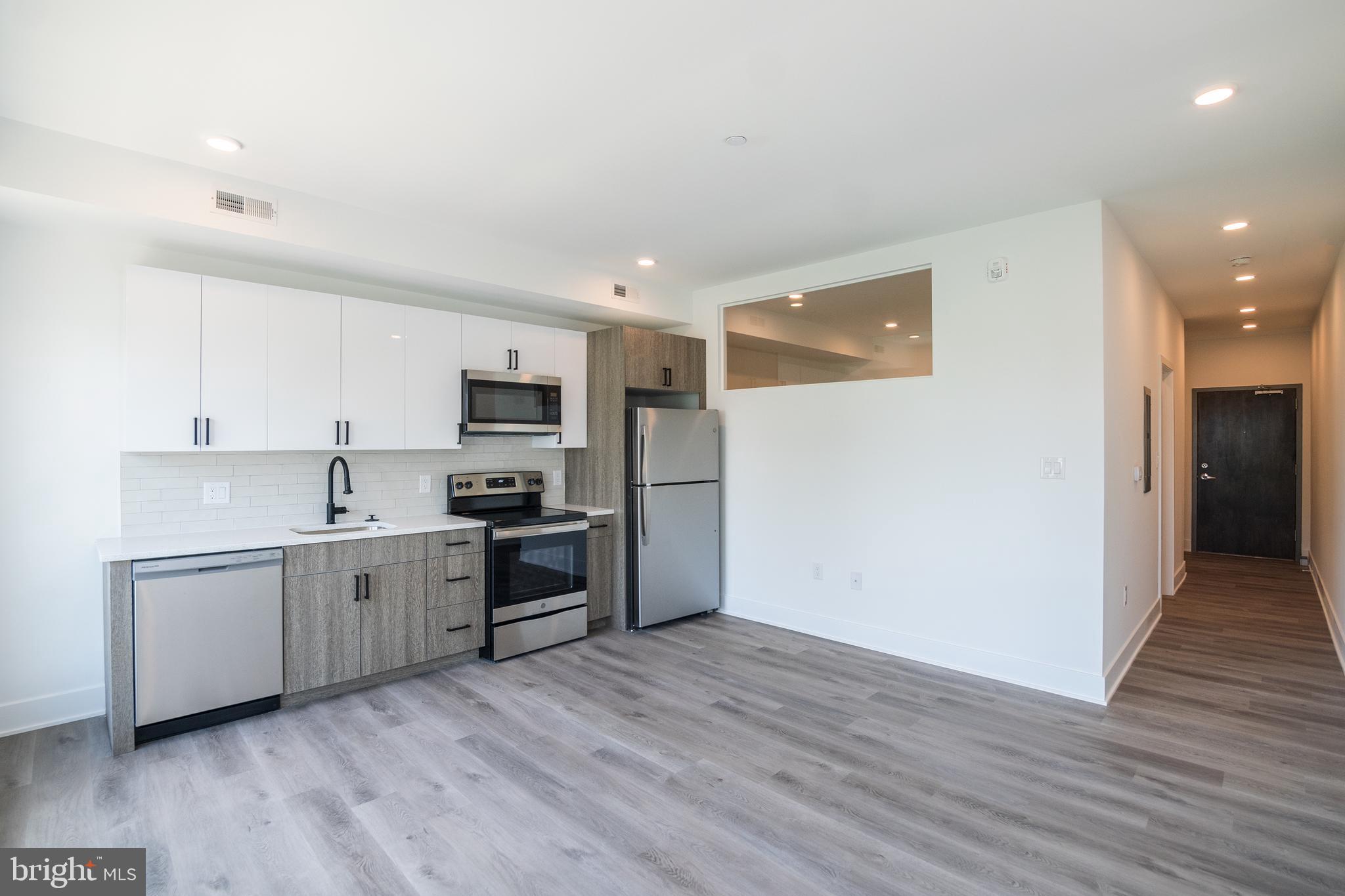 1420 Point Breeze Avenue, Unit 403 Philadelphia, PA 19146 - Photo 7 of 16 a large kitchen with stainless steel appliances granite countertop a refrigerator oven a sink dishwasher and white cabinets with wooden floor