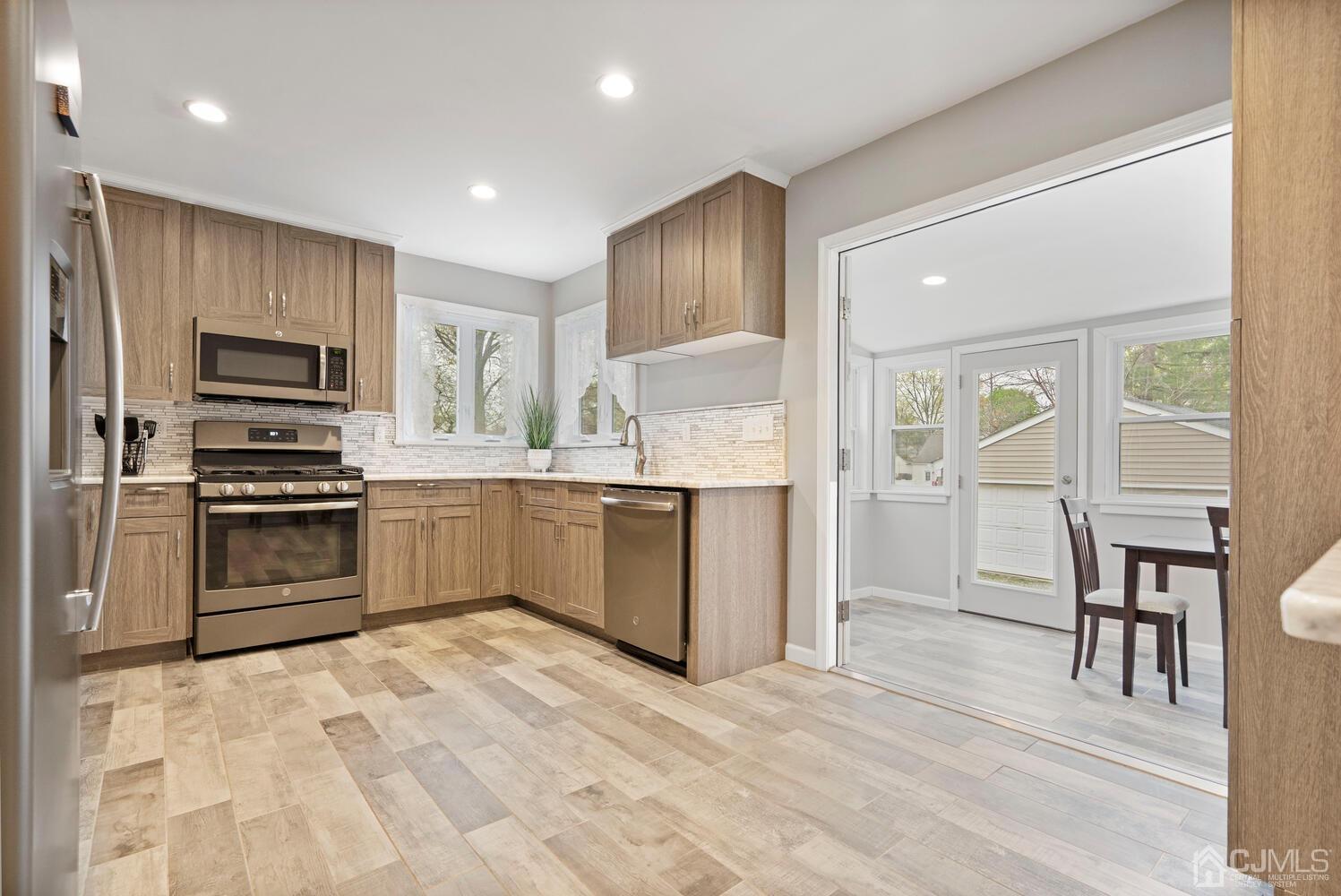 48 Lancaster Road Colonia, NJ 07067 - Photo 10 of 37 a kitchen with kitchen island granite countertop a stove top oven a sink dishwasher a dining table and chairs with wooden floor