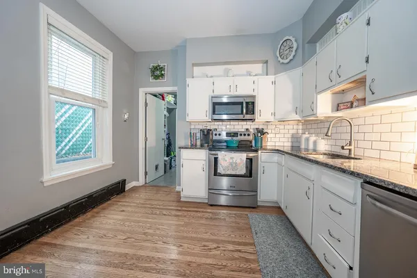 a kitchen with stainless steel appliances granite countertop a stove a sink and a microwave