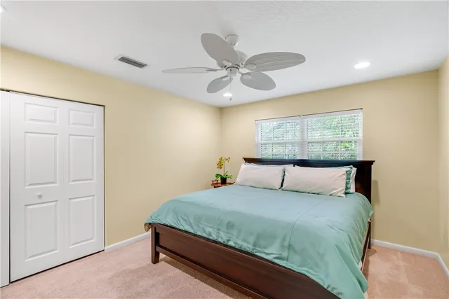 a bedroom with a large bed and a chandelier fan