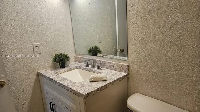 a bathroom with a granite countertop toilet sink and mirror