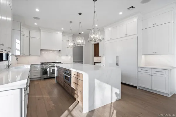 a large kitchen with granite countertop a large stove a sink a refrigerator and a stove top oven