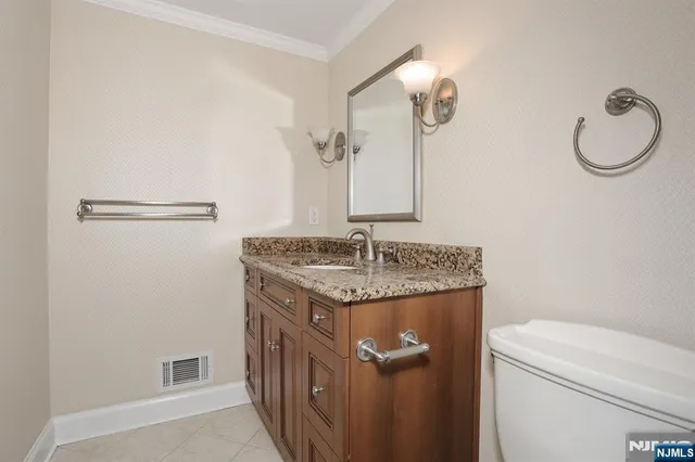 a bathroom with a granite countertop sink a toilet and a mirror