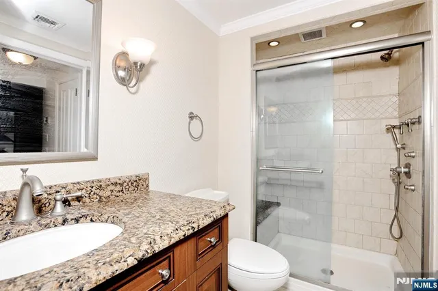 a bathroom with a granite countertop sink toilet and shower
