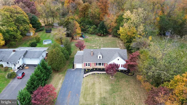 an aerial view of a house with swimming pool and large trees
