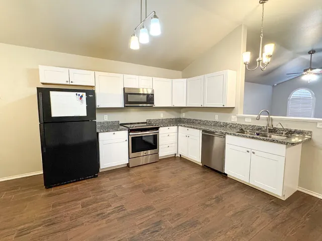 a kitchen with kitchen island granite countertop a sink cabinets stainless steel appliances and a counter top space