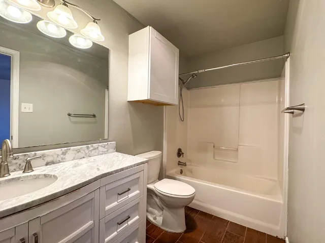a bathroom with a granite countertop sink a toilet and bathtub