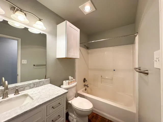 a bathroom with a granite countertop sink toilet and shower
