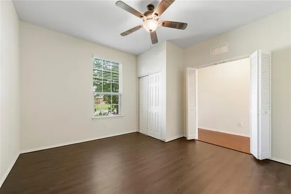 a view of an empty room with wooden floor and a window