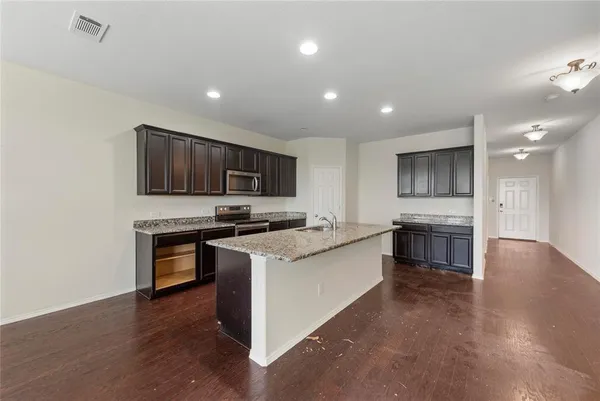 a kitchen with stainless steel appliances granite countertop a stove top oven a sink dishwasher a refrigerator and a microwave oven with wooden floor