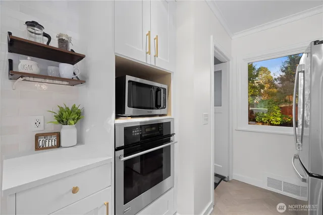 a kitchen with stainless steel appliances a stove a microwave and a potted plant