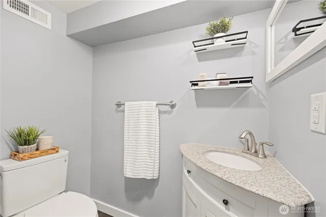 a bathroom with a granite countertop sink toilet and a mirror