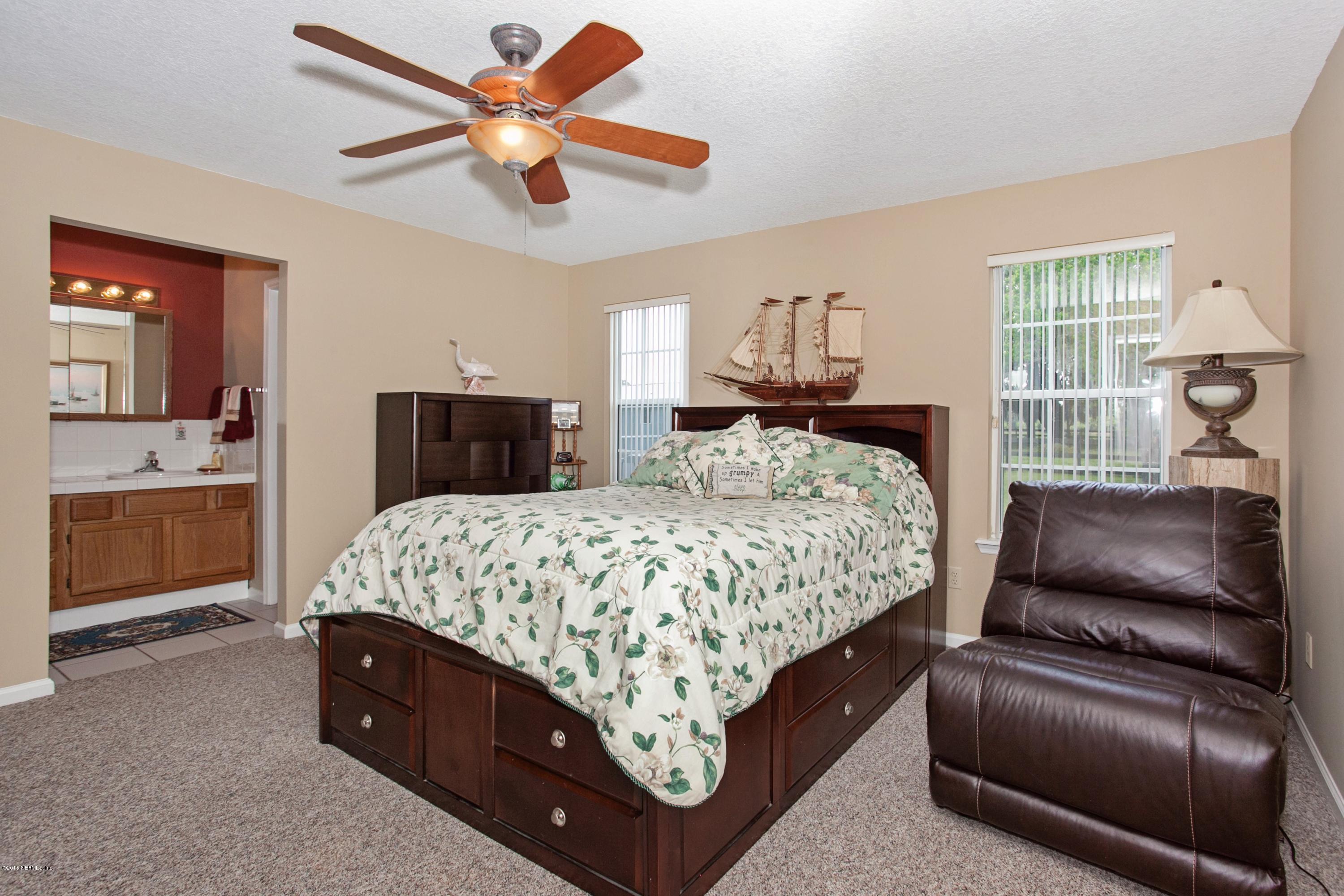 4735 Wolfe Road St. Augustine, FL 32092 - Photo 16 of 39 a bedroom with a bed a chandelier and dresser