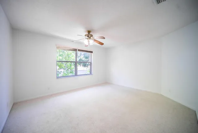 an empty room with windows and ceiling fan