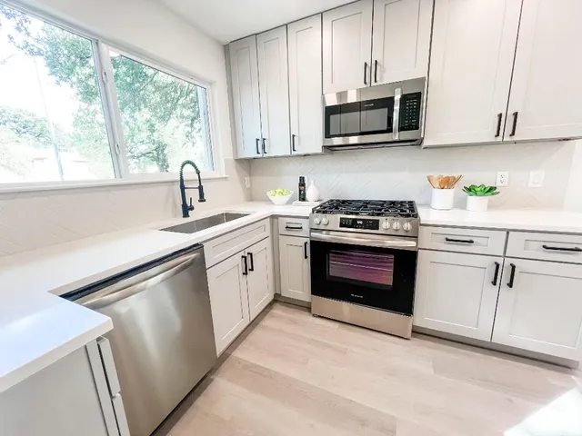 a kitchen with stainless steel appliances granite countertop a stove a sink and a microwave