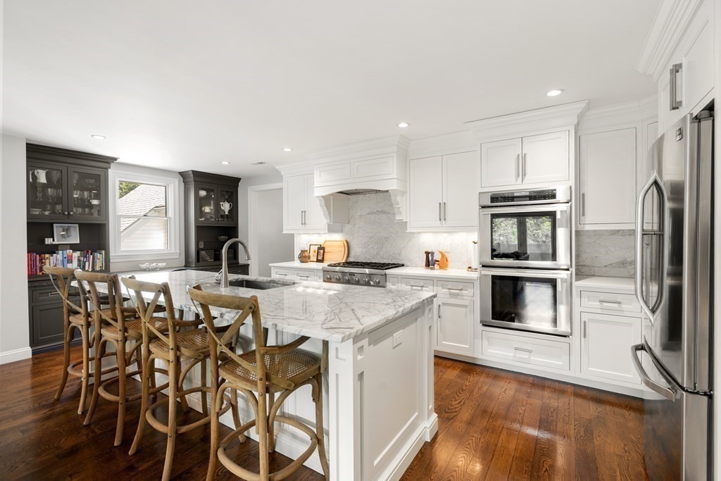 12 Puritan Road Newton, MA 02461 - Photo 1 of 39 a kitchen with stainless steel appliances kitchen island granite countertop a stove a refrigerator and a dining table with wooden floor