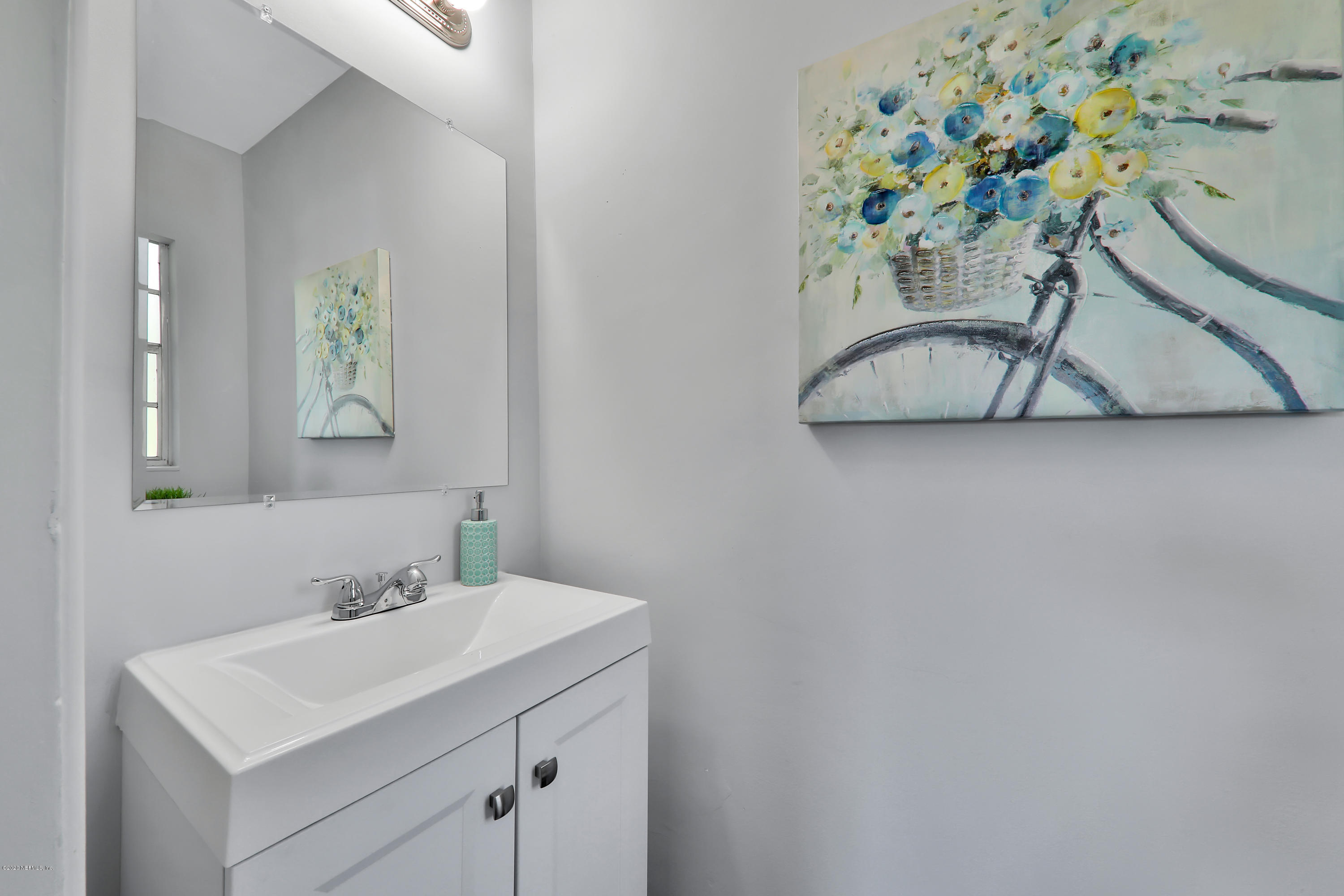 7019 Melvin Road Jacksonville, FL 32210 - Photo 14 of 22 a bathroom with a sink a mirror and a picture on a wall