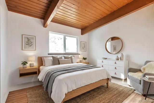 a bedroom with a bed a mirror and white walls