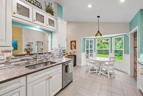 a kitchen with stainless steel appliances granite countertop a sink and a view of living room