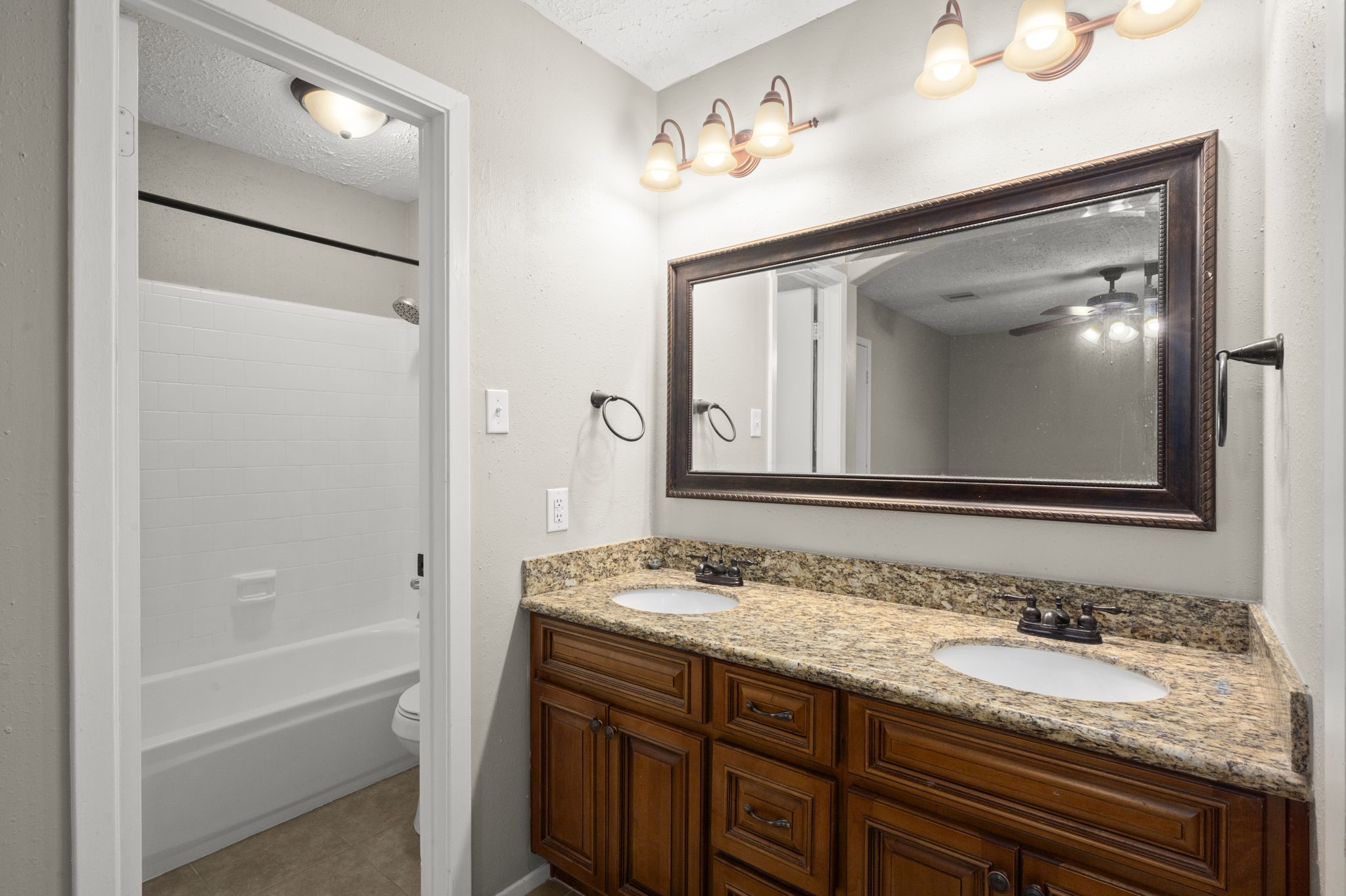 14219 Jaquine Drive Cypress, TX 77429 - Photo 11 of 16 a bathroom with a granite countertop sink tub and a mirror