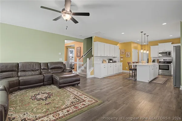 a kitchen with stainless steel appliances a refrigerator a stove a sink dishwasher and white cabinets with wooden floor