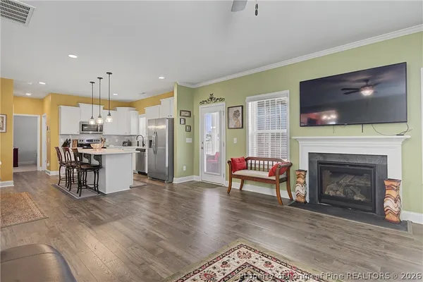 a kitchen with stainless steel appliances granite countertop a refrigerator a sink dishwasher and white cabinets with wooden floor