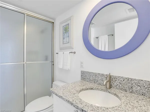 a bathroom with a granite countertop toilet sink and mirror