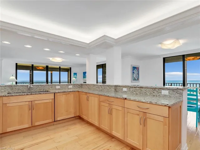 a open kitchen with granite countertop a sink and white cabinets