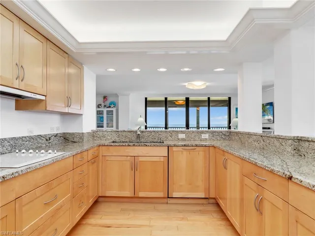 a large kitchen with granite countertop a sink and cabinets