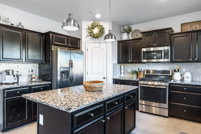 a kitchen with granite countertop a sink dishwasher stove and refrigerator with wooden floor