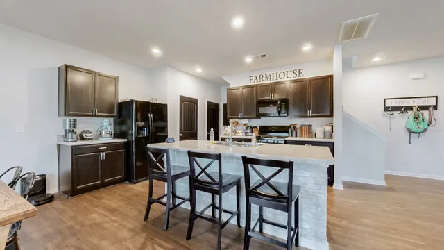 a kitchen with stainless steel appliances kitchen island granite countertop a stove a refrigerator a oven a sink with a dining table and chairs