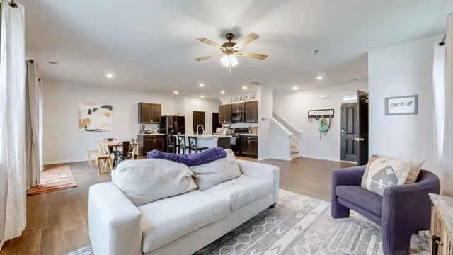 a living room with furniture kitchen view and a wooden floor