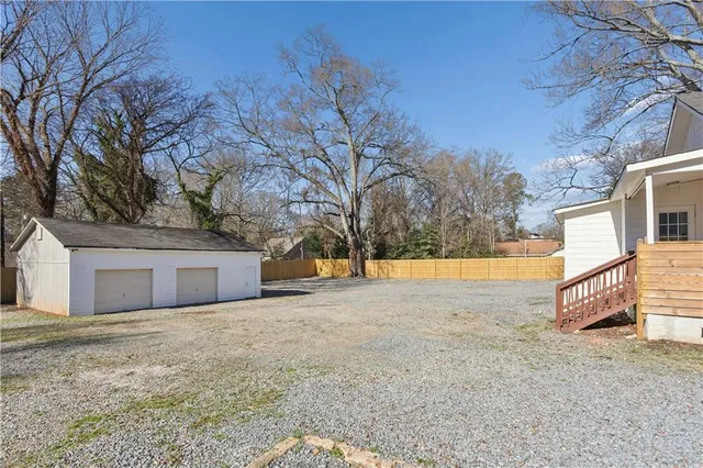 a view of a dry yard with large trees