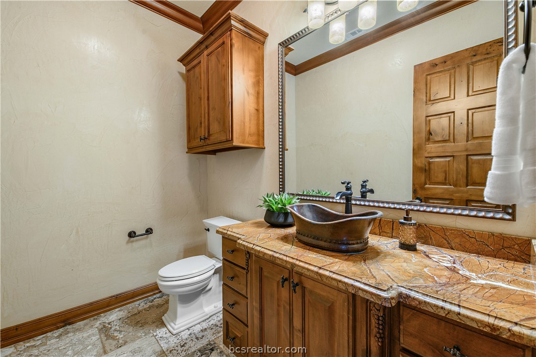 4207 Tuscany Court Bryan, TX 77802 - Photo 23 of 46 a bathroom with a granite countertop toilet a sink and a mirror