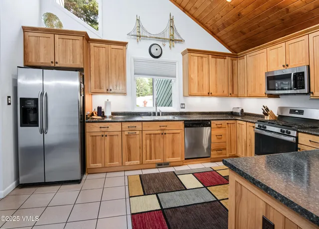 a kitchen with stainless steel appliances granite countertop a sink a stove a microwave refrigerator and cabinets