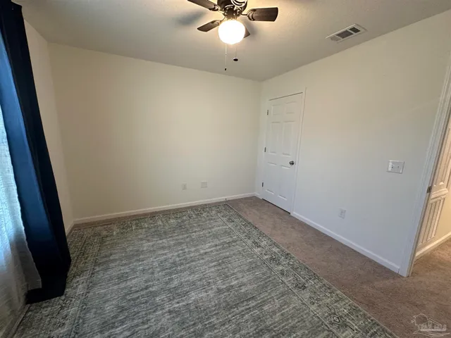 an empty room with a ceiling fan and carpet