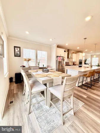 a living room with a table chairs and a dining table with wooden floor