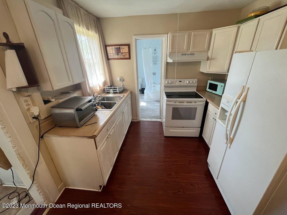 a kitchen with stainless steel appliances a stove a sink a refrigerator a washer dryer and white cabinets