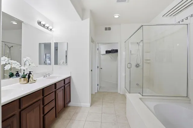 a spacious bathroom with a double vanity sink a mirror and a bathtub