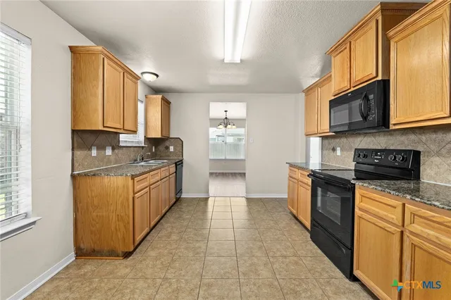 a kitchen with stainless steel appliances granite countertop a stove a sink and a microwave