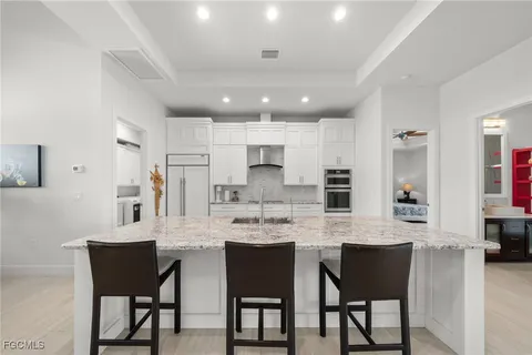 a large kitchen with stainless steel appliances kitchen island granite countertop a table chairs and a refrigerator